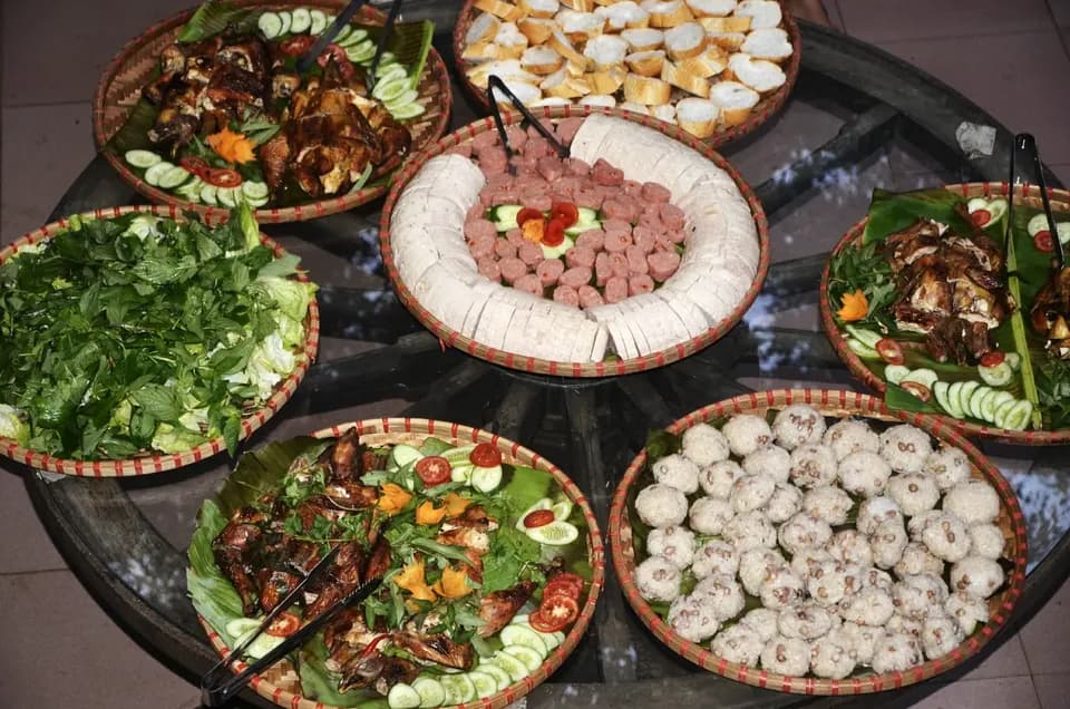 Các mẹt món nướng, chả và rau sống bày trên bàn tròn