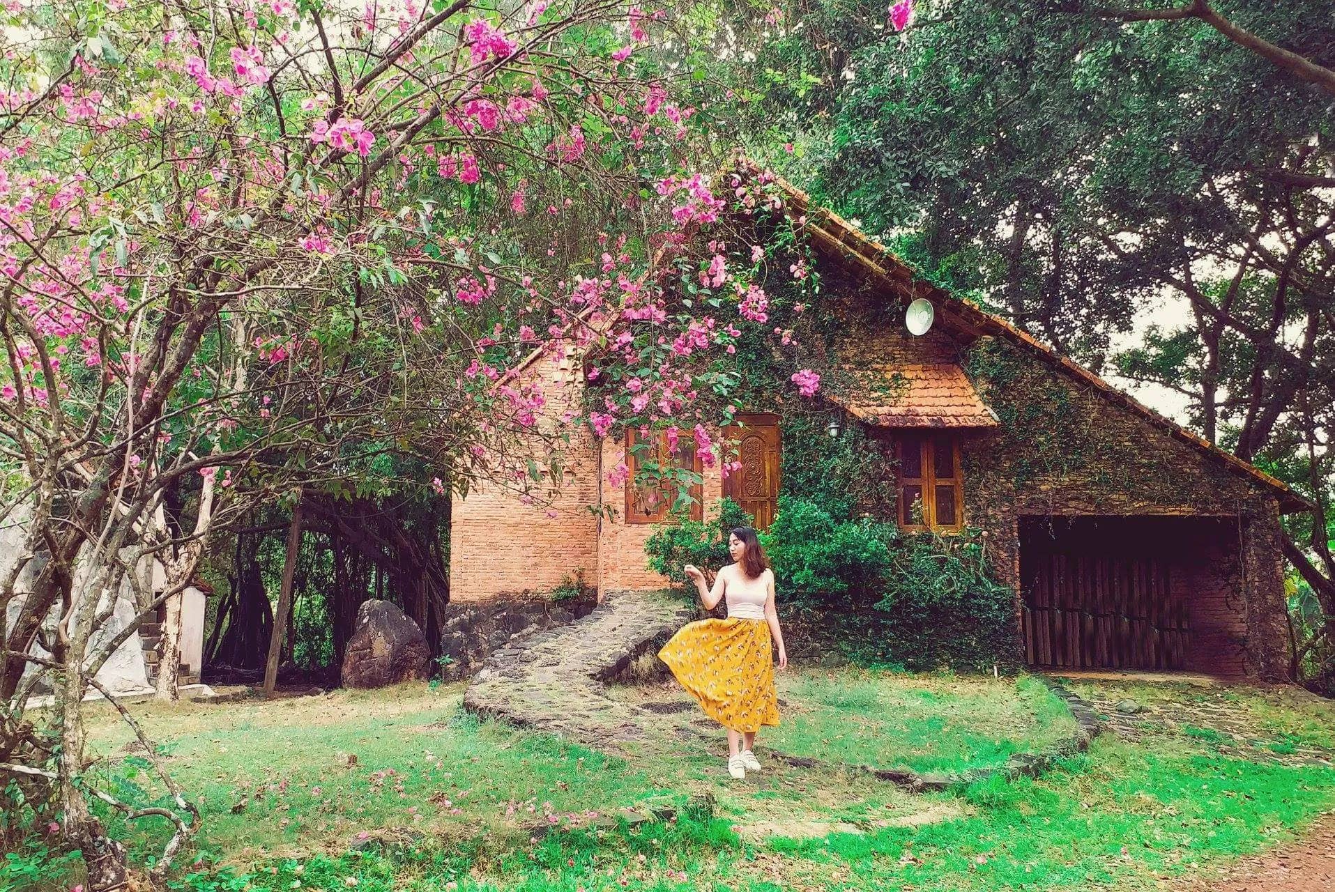 Homestay nhà thôn quê tường gạch phủ dây leo và hoa giữa vườn cây